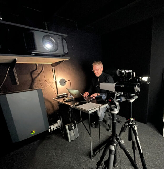 Gorm kalibrerer en JVC-projektor i AVshops kalibreringsrom med bærbar PC og profesjonelt måleutstyr. Retusjert originalfoto.